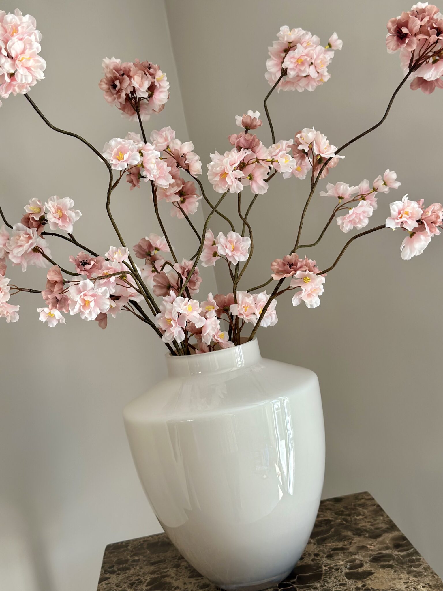 Beige vaas met roze zijden bloesemtakken