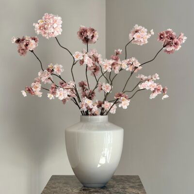 Beige vaas met roze zijden bloesemtakken