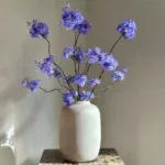 Beige vaas mat met blauw paars zijden bloesemtakken