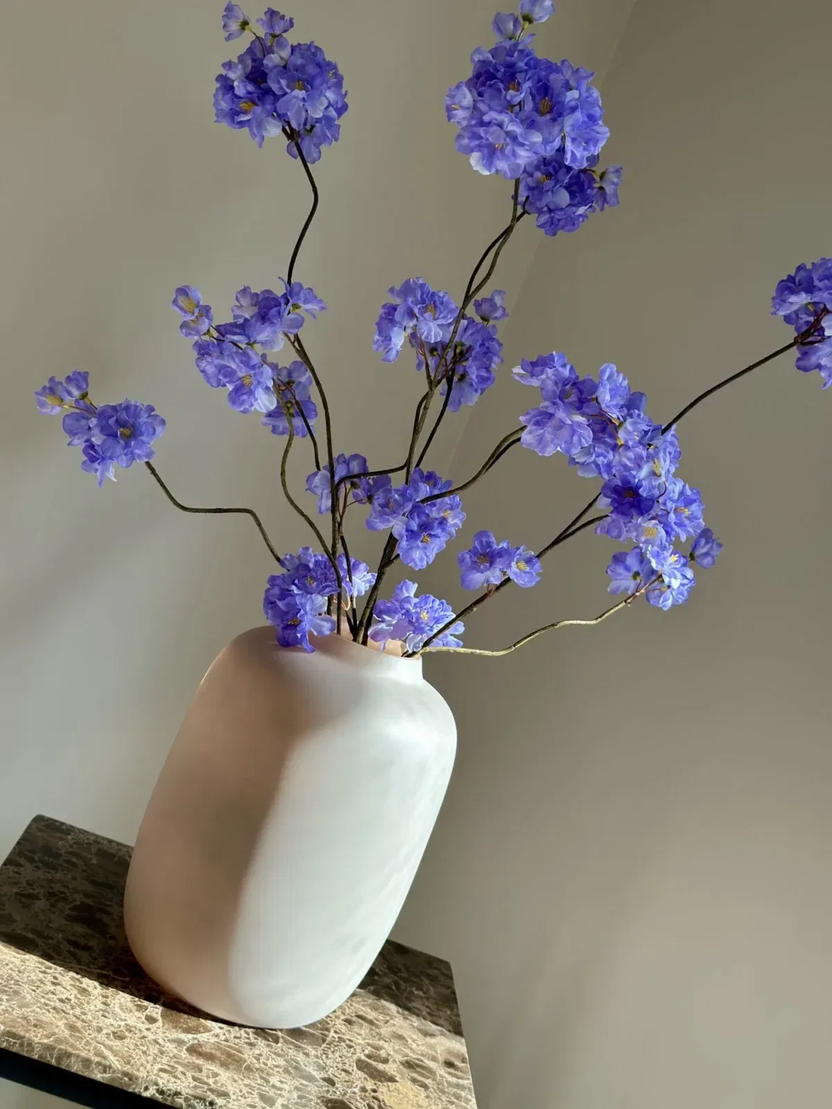 blauw paars zijden bloesemtakken met matte beige vaas