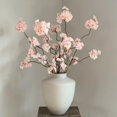 Beige vaas met roze zijden bloesemtakken